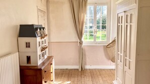 A room with a wooden floor, a dresser, a window with curtains, and a view of greenery outside. - Le Vieux Logis, an idyllic setting (Varengeville-sur-Mer)