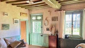 A cozy room with a green door, a wooden table with candles, a floral armchair, and a window with curtains. - Le Vieux Logis, an idyllic setting (Varengeville-sur-Mer)