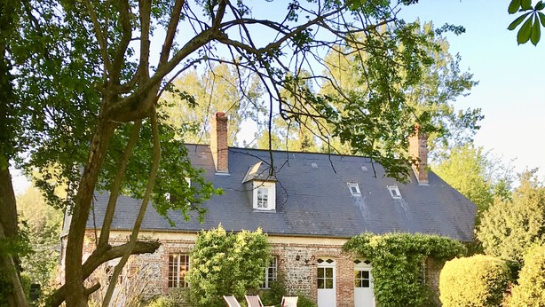 A stone house with a sloped roof, surrounded by a well-maintained lawn and flowering plants. - Le Vieux Logis, an idyllic setting (Varengeville-sur-Mer)