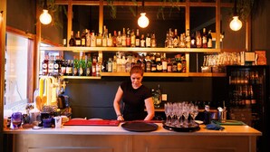 Un espace bar avec des étagères remplies de bouteilles et de verres, et un barman qui prépare des boissons.