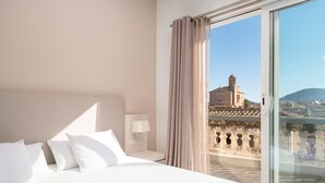 Une chambre d’hôtel avec un grand lit, une table de chevet, une lampe et une vue sur un immeuble par la fenêtre.