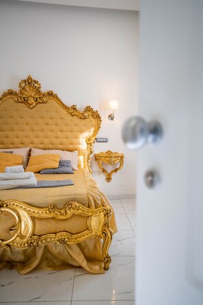 Un lit luxueux agrémenté de motifs dorés ouvragés, une table de chevet et un luminaire fixé au mur.