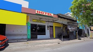 A hotel with a prominent red sign, a yellow facade, and a closed shuttered entrance. - OYO 91695 Hotel Benteng Portugis (Sidoarjo)