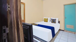 A hotel room with a bed, a television, and a door. - OYO 91695 Hotel Benteng Portugis (Sidoarjo)