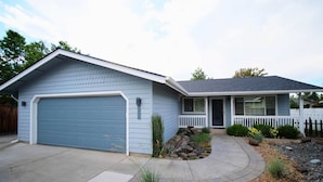Ein eingeschossiges Haus mit blauer Garage, einer Veranda und einem gepflegten Vorgarten.