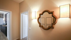 A hallway with a wooden floor, a white door, and a wall-mounted mirror with a rope design. - Apartments Florence - Novella Bloom (Florence)