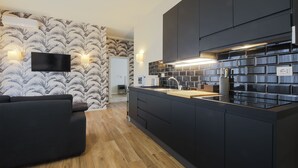 A modern kitchen with a black countertop, built-in appliances, and a flat-screen TV mounted on the wall. - Apartments Florence - Novella Bloom (Florence)