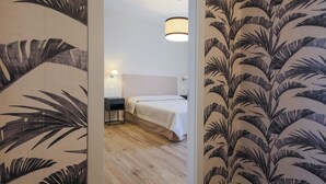 A hotel room with a bed, a nightstand, a lamp, and a wooden floor. - Apartments Florence - Novella Bloom (Florence)