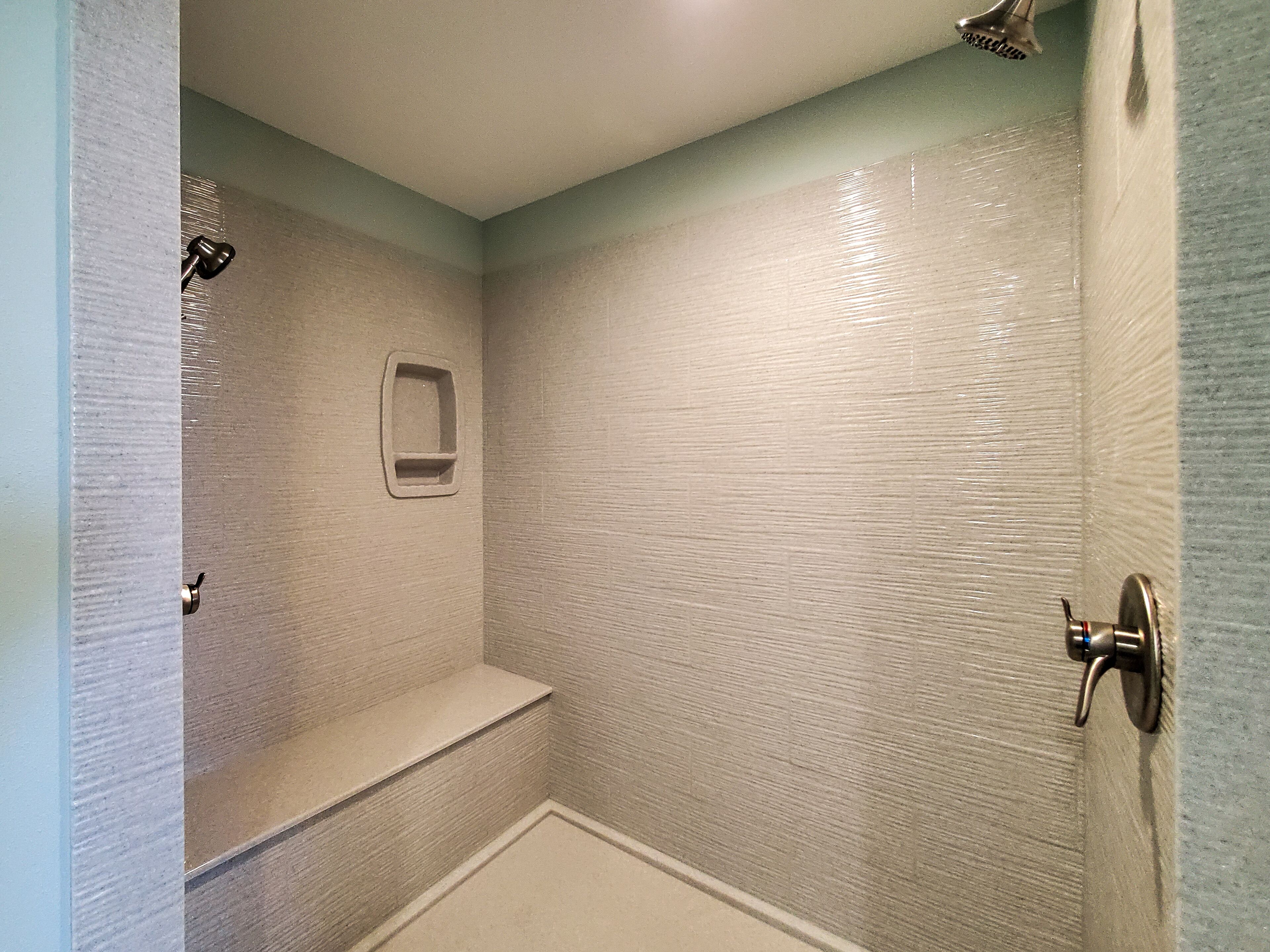 Baño con ducha, un banco y un estante pequeño.