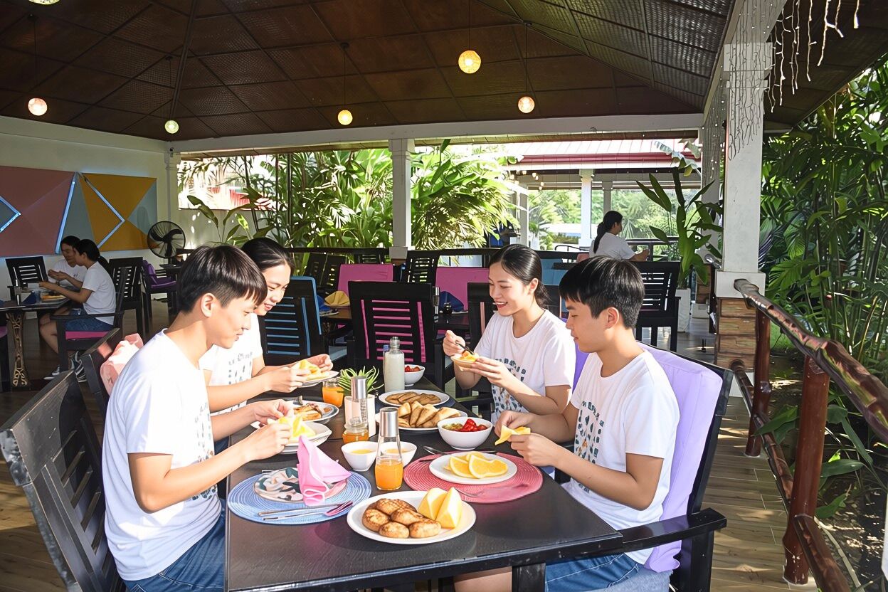 A group of people dining at an outdoor restaurant with tables, chairs, and various food items.