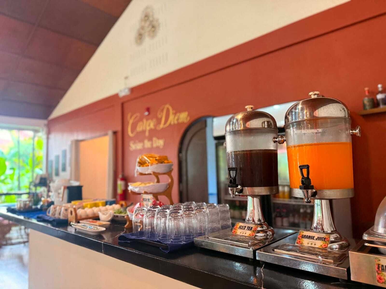 Un espace dédié au café, avec des distributeurs de thé glacé et de jus d’orange, un présentoir à gâteaux et une pancarte sur laquelle on peut lire : « Carpe Diem ».