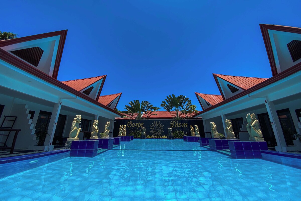 A swimming pool with statues and a building with a red roof.