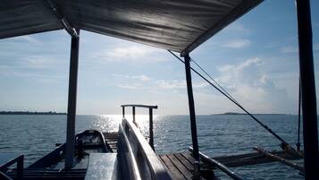 Cubierta de barco con barandilla metálica, un banco y un toldo.