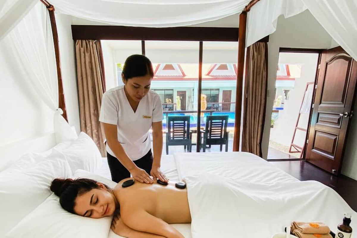 Une pièce comprenant un lit, une table de massage et donnant sur l’extérieur.