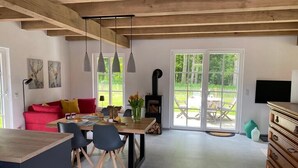 A modern kitchen with a dining area, a red sofa, and a fireplace. - New charming half-timbered house by the lake in the idyllic Münsterland region (Warendorf)