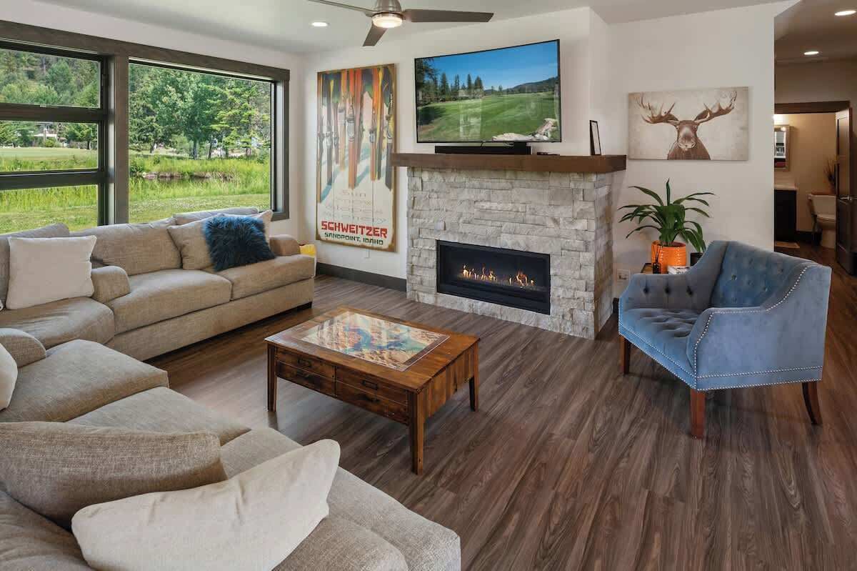 A living room with a stone fireplace, a large TV, and a view of the outdoors.