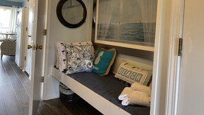 A cozy room with a built-in bench, a mirror, and a framed picture of the sea.