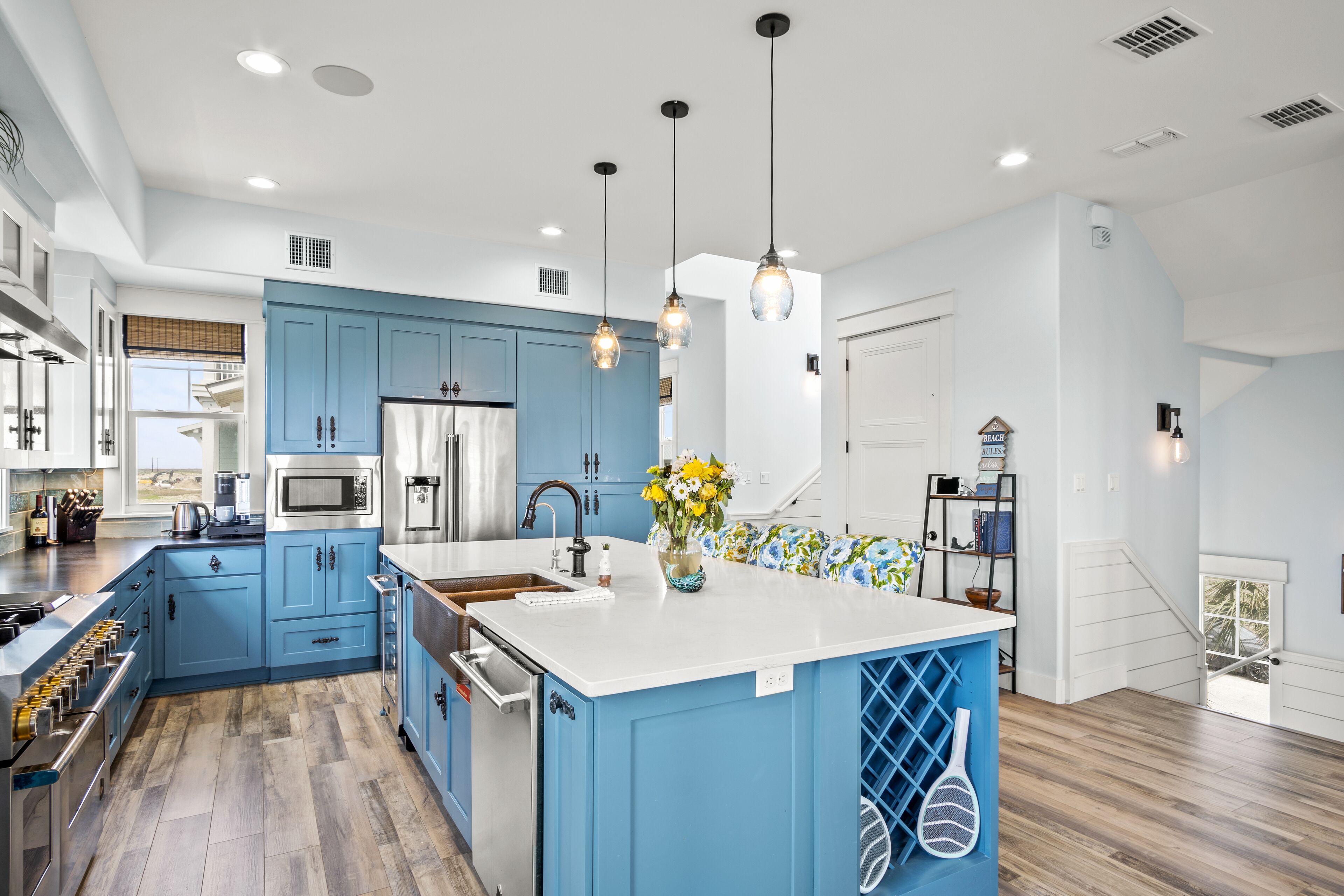 A modern kitchen with blue cabinets, a white island, and pendant lighting.