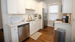 Una cocina moderna con armarios blancos, electrodomésticos de acero inoxidable y suelo de madera.