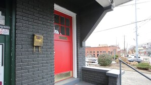 Un edificio con puerta roja, buzón y felpudo en el exterior.