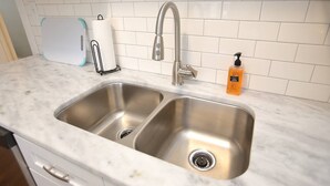 Una cocina con dos lavamanos de acero inoxidable, un dispensador de toallas de papel y un dispensador de jabón.