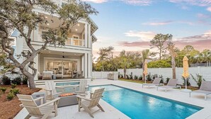 A two-story house with a swimming pool, outdoor seating, and a fire pit.