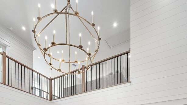 A spacious kitchen with a central island, wooden flooring, and a chandelier.