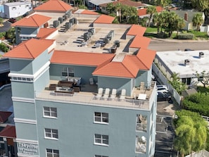 Hotel com vários andares e terraço no telhado, com área de estar externa e unidades de ar condicionado.