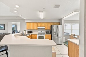 A modern kitchen with wooden cabinets, stainless steel appliances, and a large island. - Penthouse condo with amazing views! Private 1000 sf balcony (Madeira Beach)