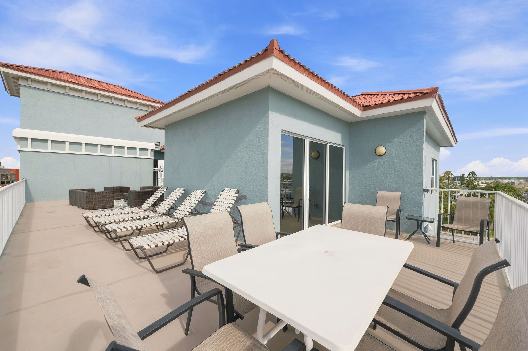 Une terrasse sur le toit avec une table et des chaises, un espace salon couvert et une vue sur le paysage environnant.