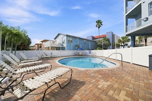 Une piscine avec des chaises longues et une terrasse en briques.