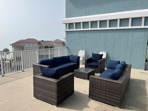 A balcony with wicker furniture and a view of a building with red-tiled roofs. - Penthouse condo with amazing views! Private 1000 sf balcony (Madeira Beach)