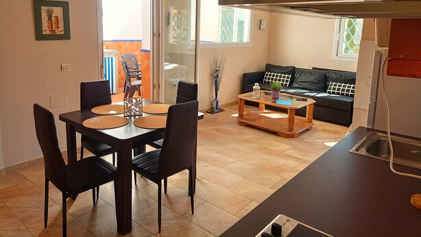 A modern living room with a dining area, a sofa, and a kitchen counter. - G-3 Studio with patio and mountain views. (Malaga)
