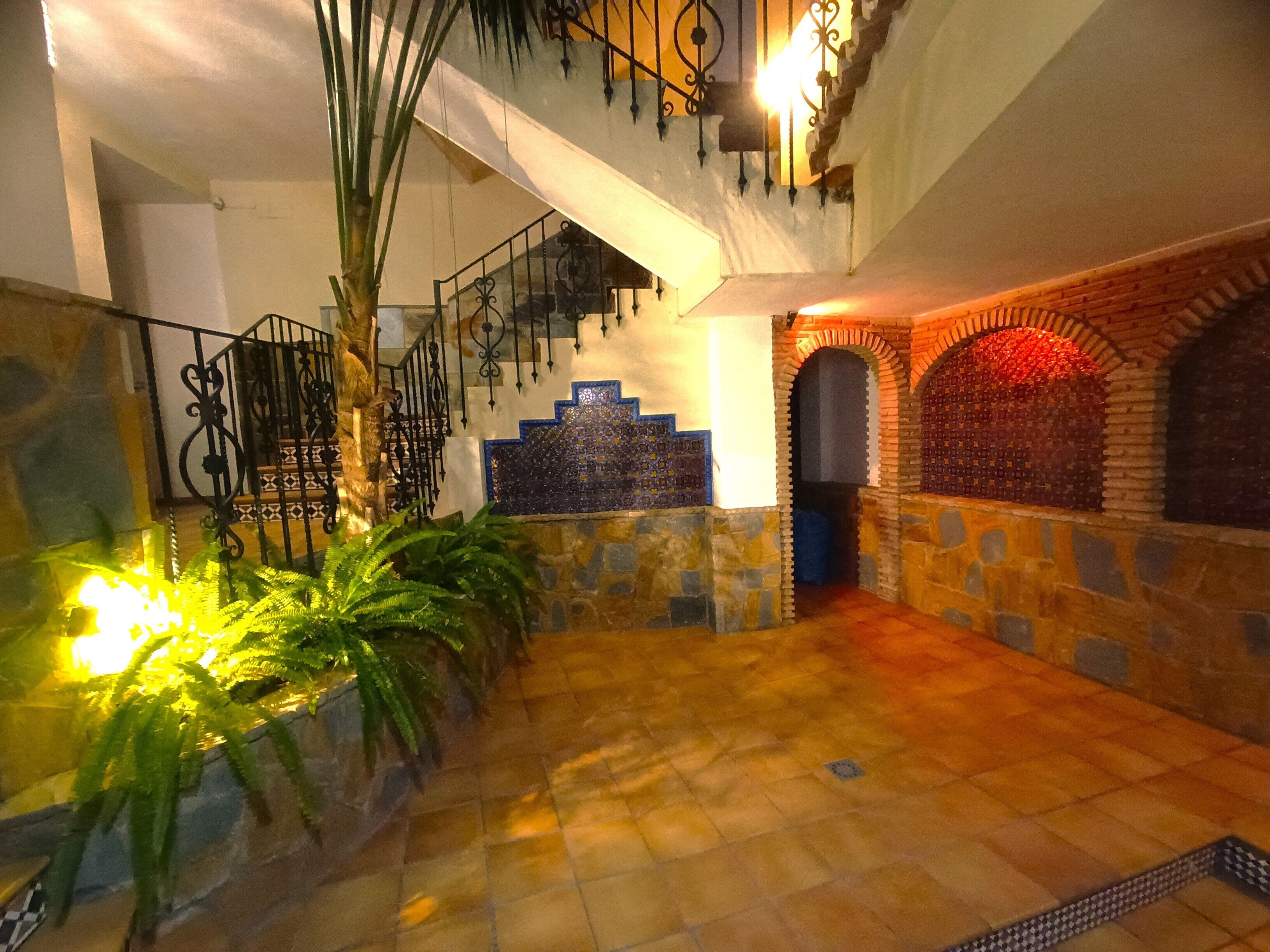 A spacious indoor area with a staircase, stone walls, and a tiled floor.