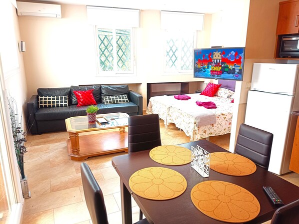 A modern living room with a sofa, coffee table, and a dining area with a table and chairs.