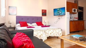 A modern bedroom with a large bed, a sofa, a coffee table, and a kitchen area with wooden cabinets and a microwave. - G-3 Studio with patio and mountain views. (Malaga)