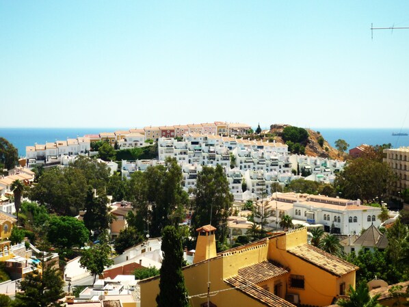 A coastal town with densely packed white buildings, some with balconies, and a clear view of the sea.