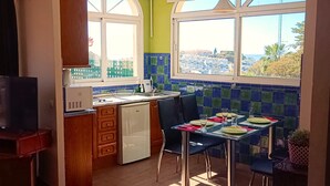 Een keuken met een eethoek, grote ramen en uitzicht op een stadsgezicht.