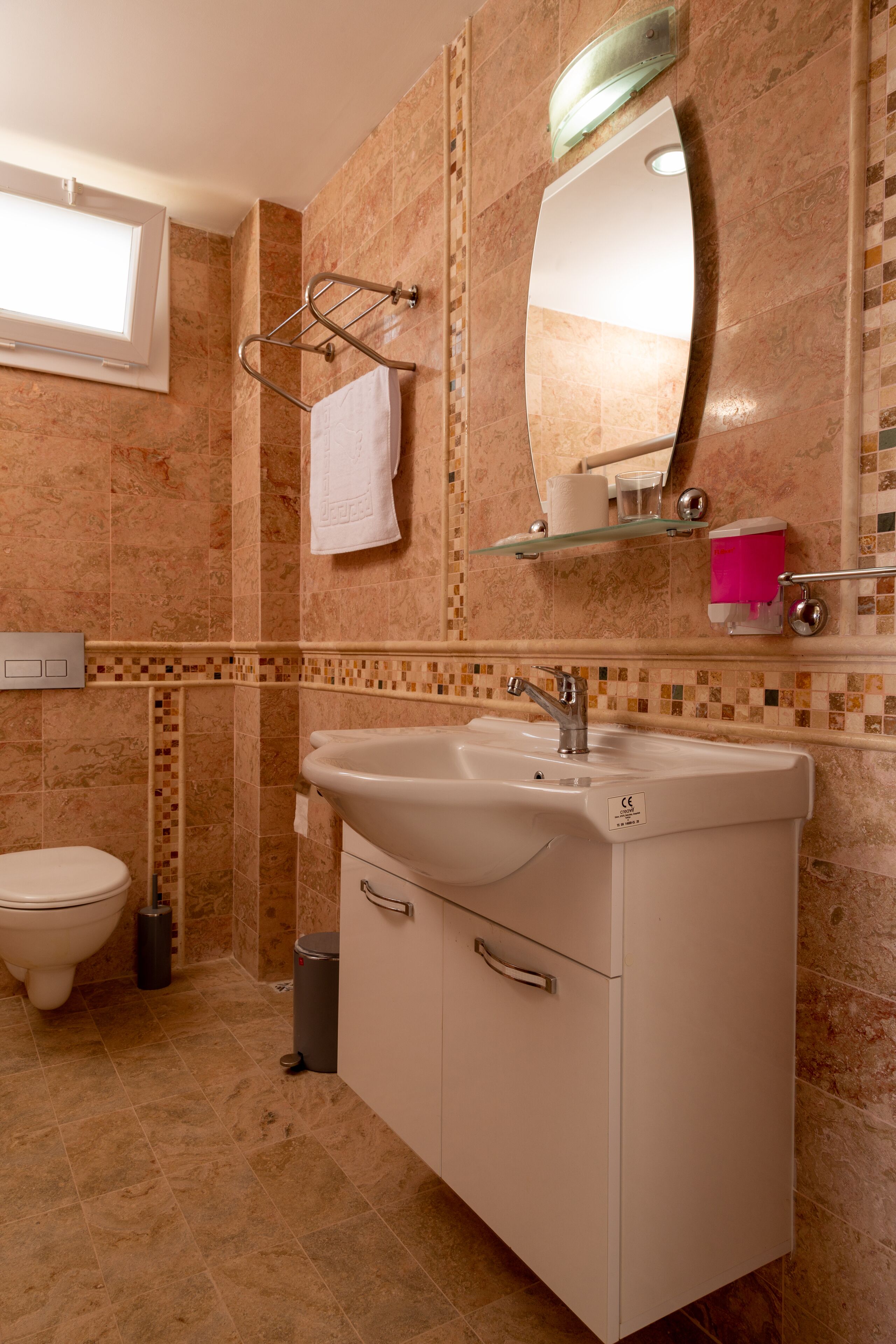 A bathroom with a sink, mirror, towel rack, and toilet.