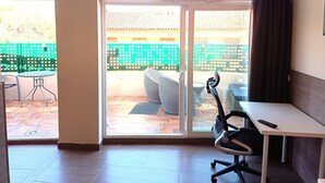 A room with a sliding glass door leading to an outdoor patio, a white desk with a chair, and a small table with chairs. - D-2 Apartment with a terrace. (Malaga)