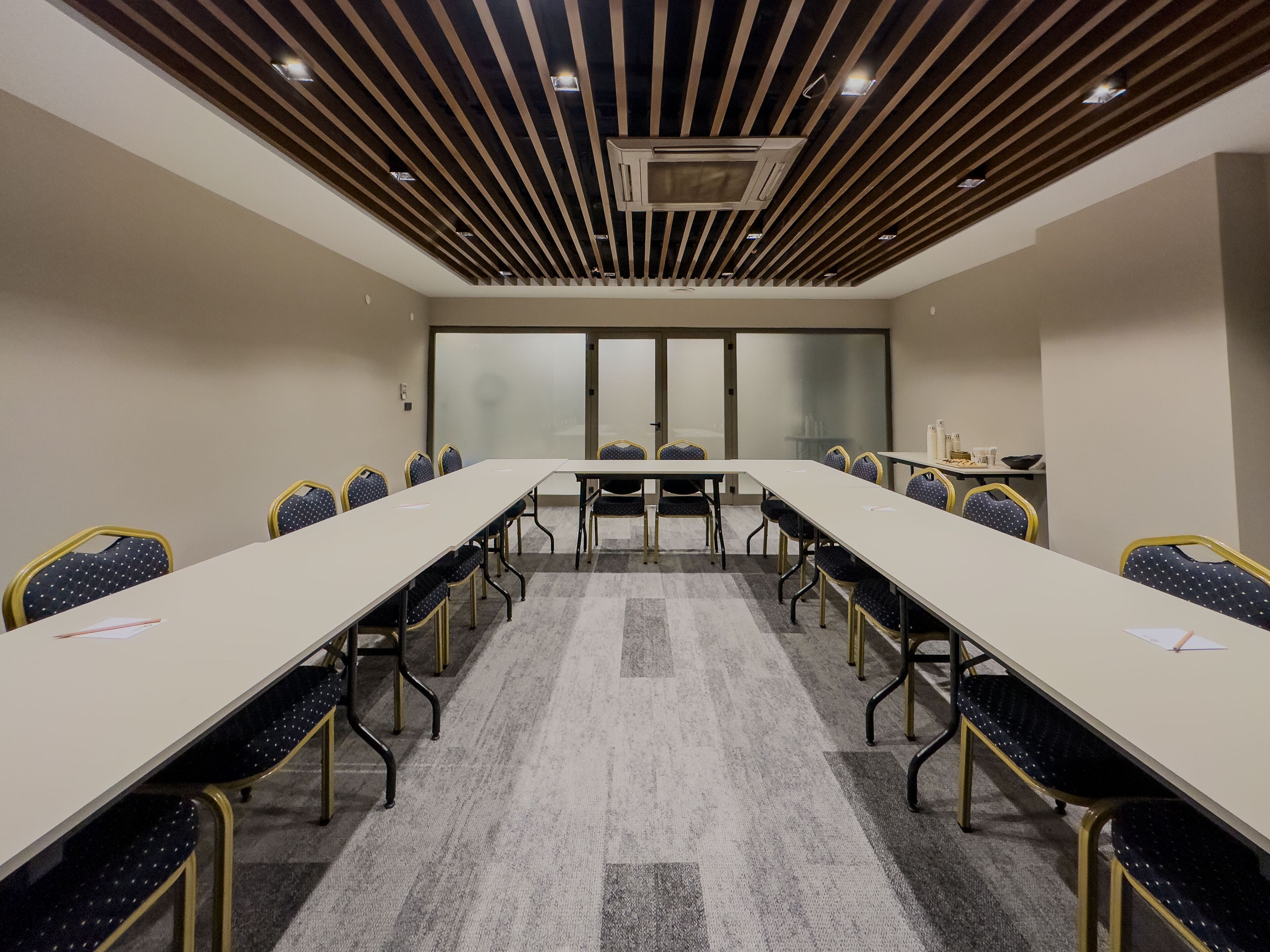 Une salle de conférence avec une longue table, des chaises et un sol recouvert de moquette.