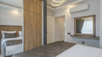 A hotel room with two beds, a wooden panel wall, a large mirror, and a modern light fixture.