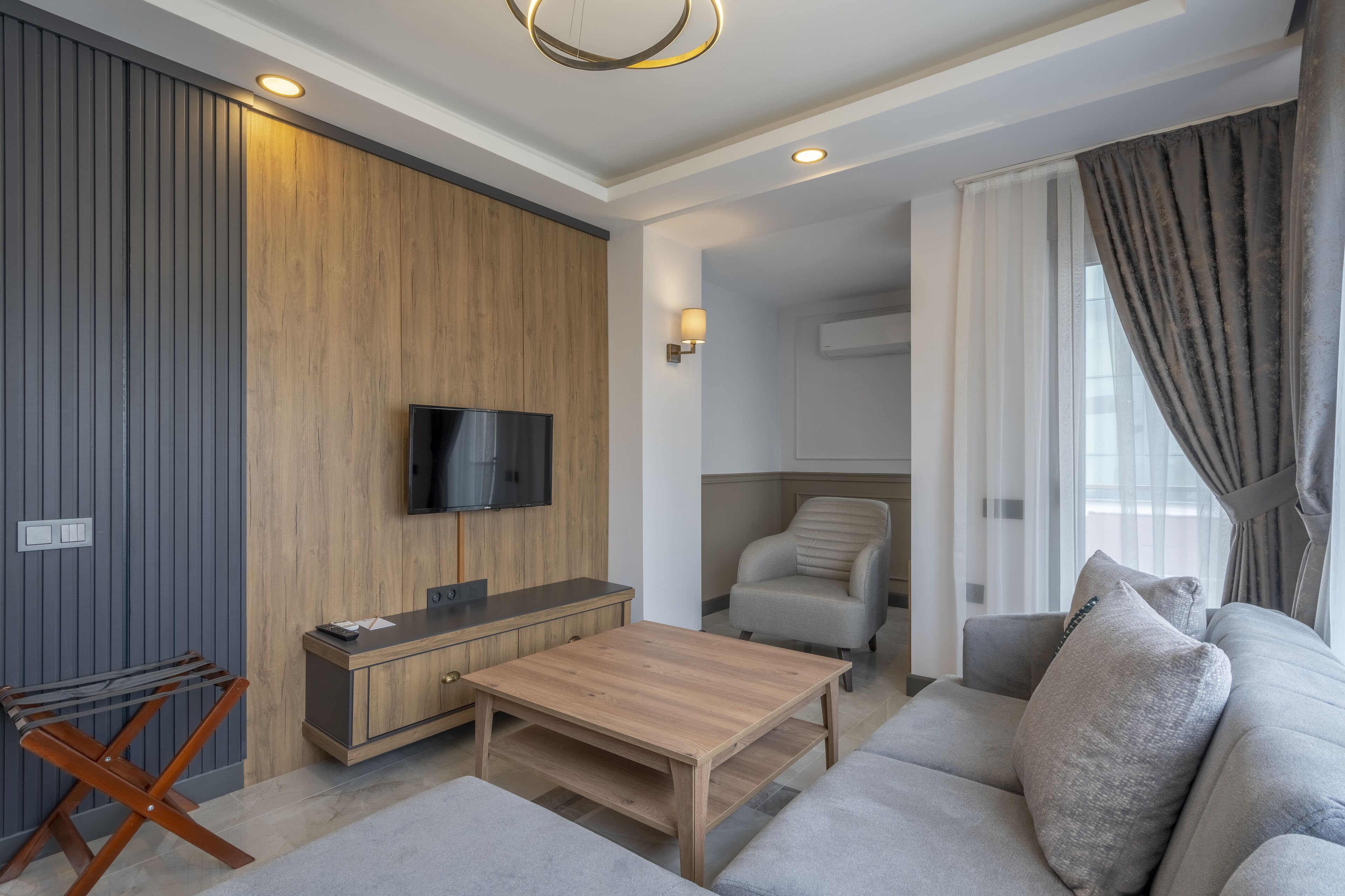 Ein modernes Wohnzimmer mit einer Wand in Holzoptik, einem Flachbildfernseher, einer Couch und einem Couchtisch.