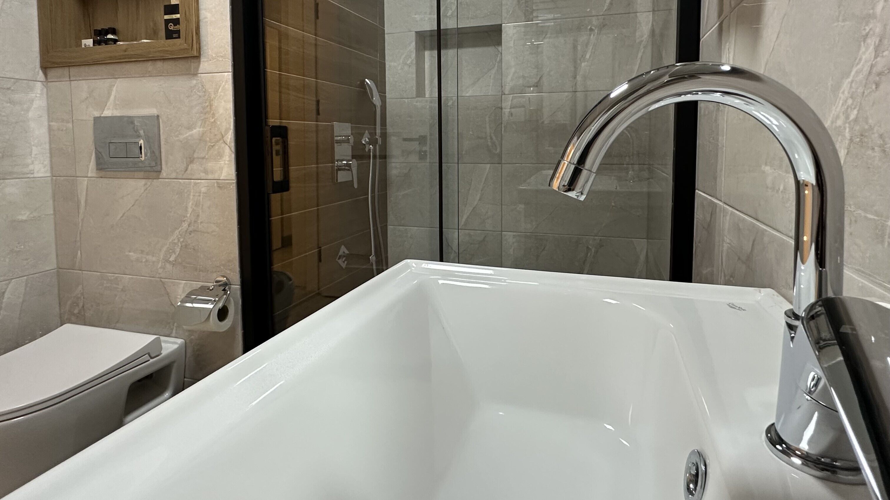 Un baño moderno con una bañera blanca, un box de ducha de vidrio y un inodoro.