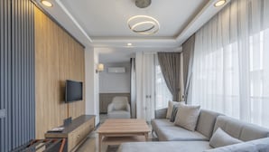 A modern living room with a sofa, a coffee table, and a TV mounted on the wall. - Quality Gold Suit Hotel (Antalya)