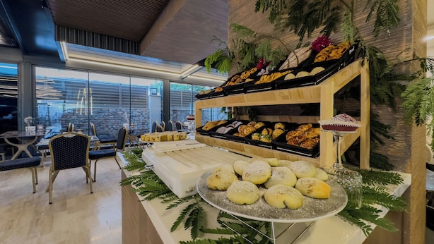 A buffet area with various baked goods displayed on wooden shelves and a central serving tray. - Quality Gold Suit Hotel (Antalya)