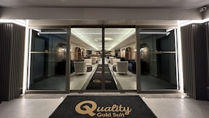A hotel entrance with a mirrored wall reflecting the interior, a reception desk, and seating areas. - Quality Gold Suit Hotel (Antalya)