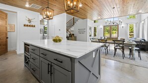A spacious kitchen with a large island, wooden ceiling, and modern lighting fixtures. - Broken Bow Secluded Playset Retreat for Families (Broken Bow)