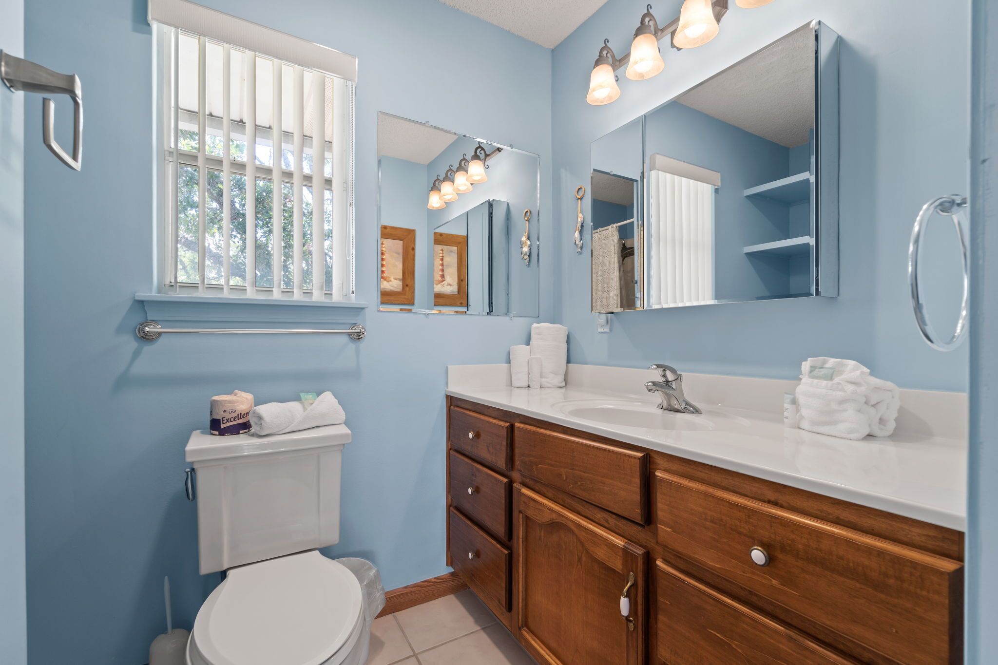 A bathroom with a white toilet, a sink with a mirror above it, and wooden cabinets.