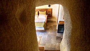 A rustic interior with a stone staircase leading to a bedroom with a bed and a wooden headboard.